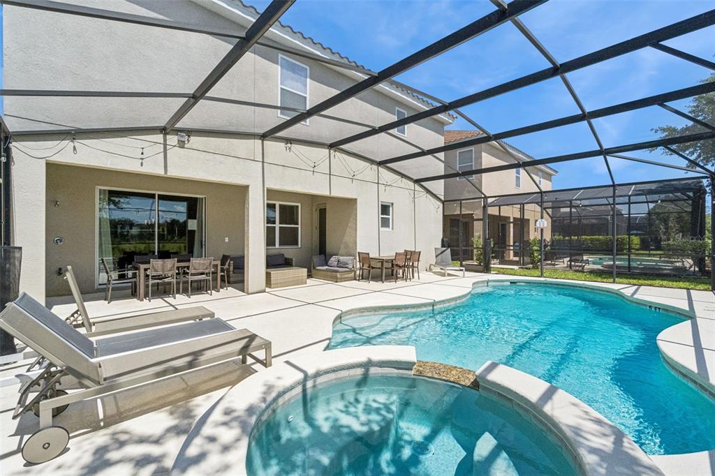 A screened-in patio features a swimming pool, a hot tub, and outdoor dining furniture — 5304 OAKBOURNE AVENUE, DAVENPORT, FL