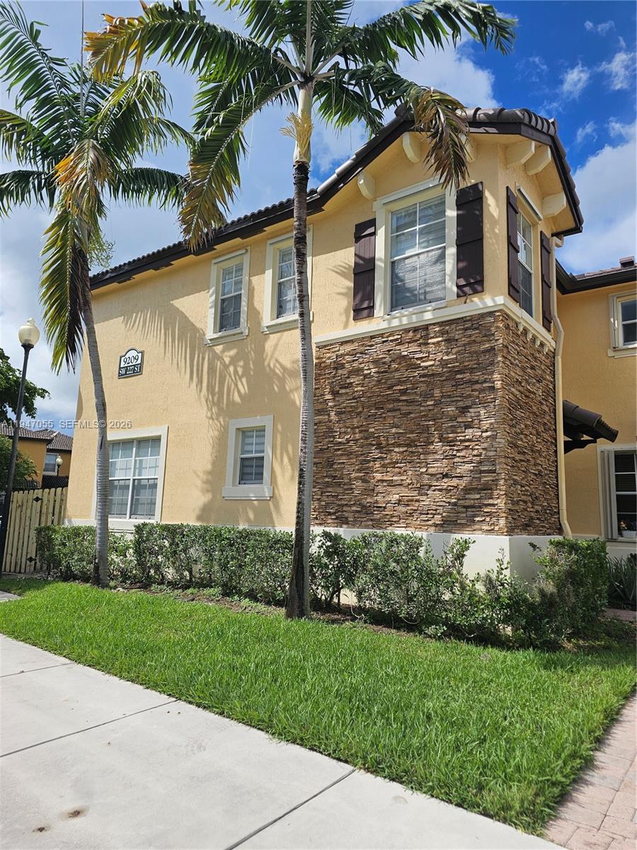 A two-story stucco house features a stone facade, brown shutters, and tall palm trees — 9209 SW 227th St # 1, Cutler Bay FL 33190, CUTLER BAY, FL