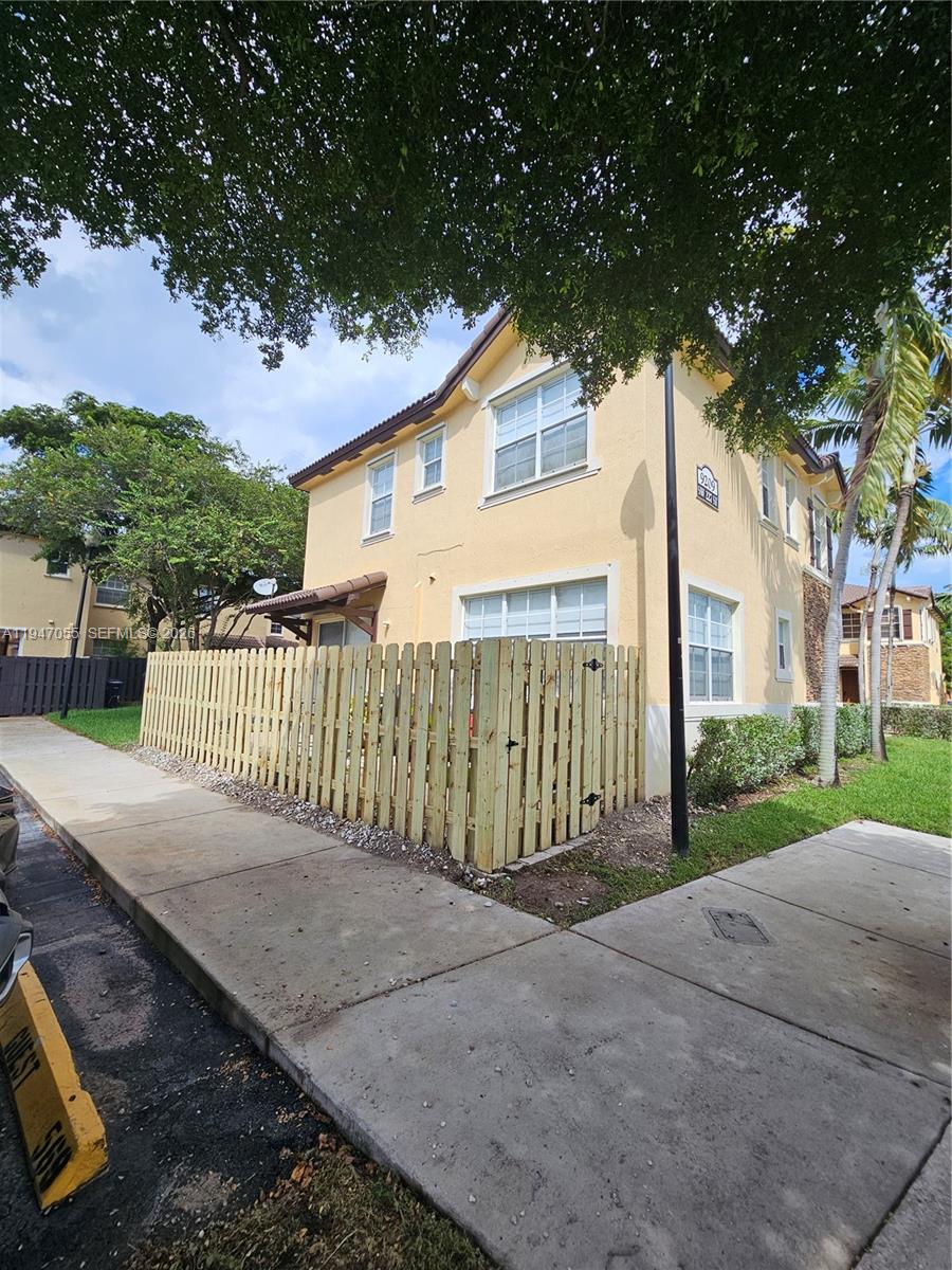 A two-story yellow stucco house features a wooden privacy fence and a concrete sidewalk — 9209 SW 227th St # 1, Cutler Bay FL 33190, CUTLER BAY, FL