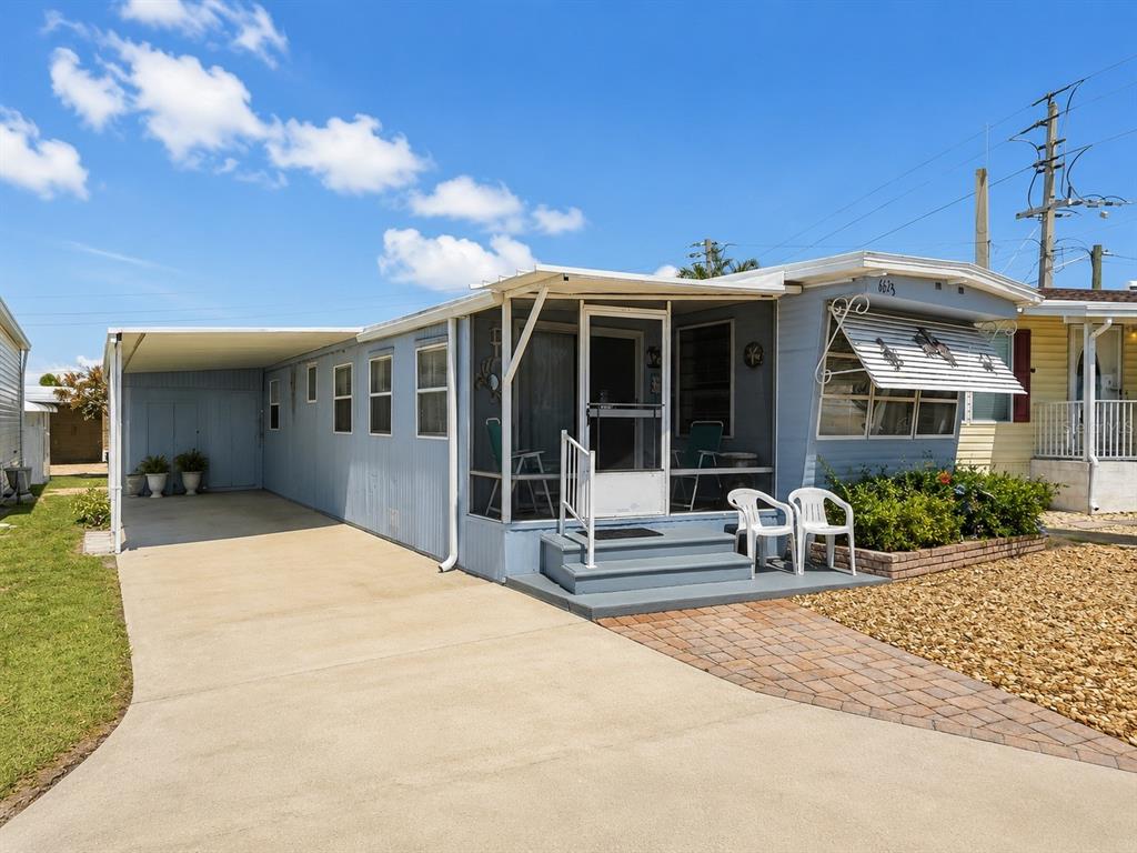 A light blue mobile home with a carport, screened porch, and concrete driveway — 6623 WASHINGTON STREET, BRADENTON, FL