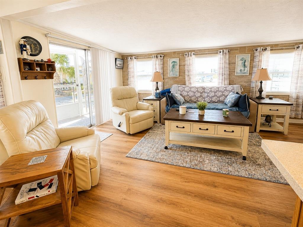 A living room features light wood flooring, two cream recliners, a sofa, and a coffee table — 6623 WASHINGTON STREET, BRADENTON, FL