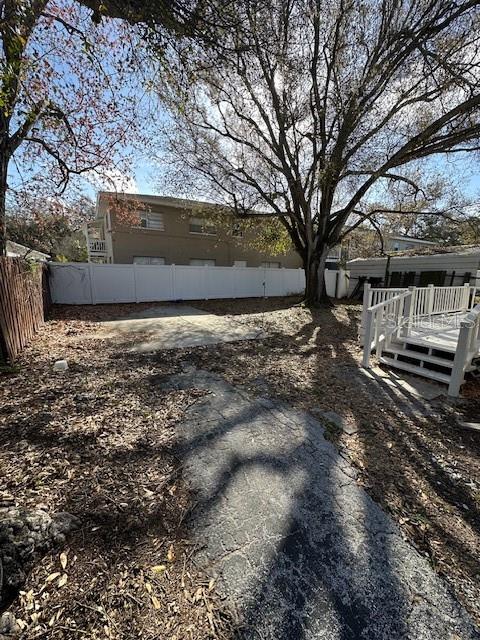 A backyard features a concrete patio, a white fence, and a wooden deck — 1587 SCRANTON AVENUE UNIT B, CLEARWATER, FL