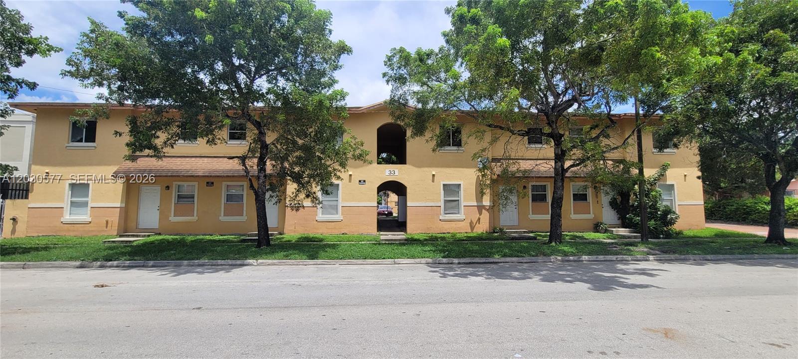 A two-story yellow apartment building with multiple windows and doors faces a paved street — 33 E 20th St # 203, Hialeah FL 33010, HIALEAH, FL