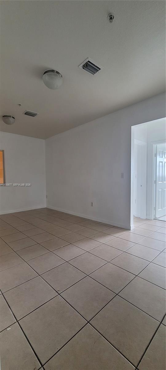 An empty room features beige tile flooring, white walls, and two ceiling-mounted light fixtures — 33 E 20th St # 203, Hialeah FL 33010, HIALEAH, FL
