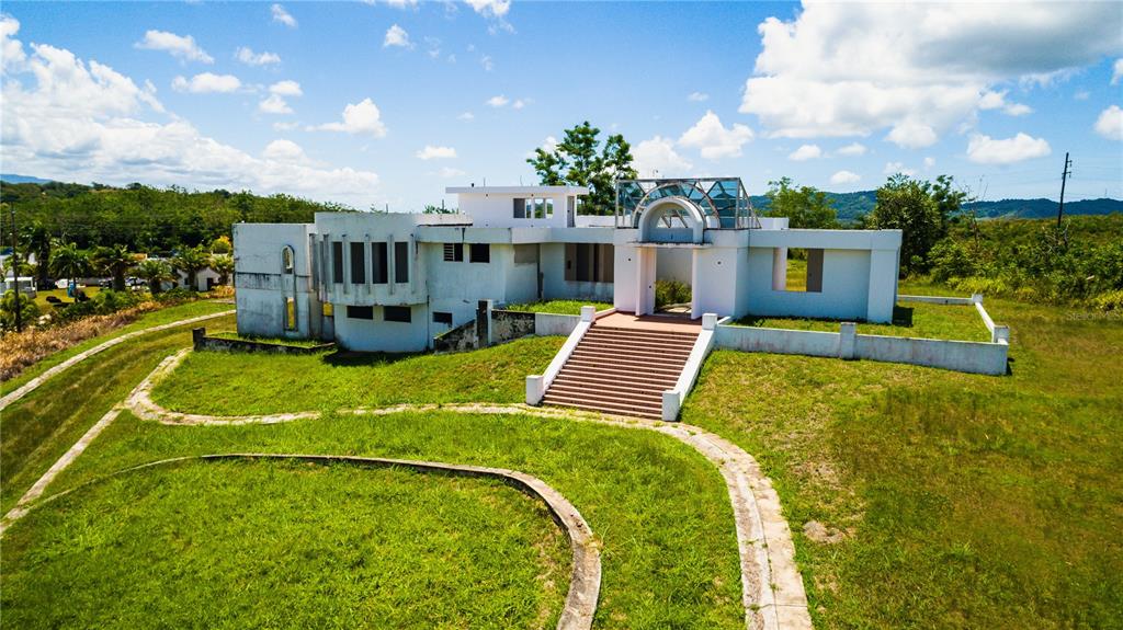 An aerial view of a modern, unfinished white concrete house with a prominent front staircase — PR 311 KM 2.8 BO. GUANAJIBO SECTOR LAS DELICIAS, CABO ROJO, PR