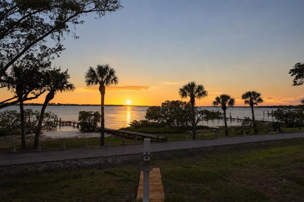 A sunset view over a waterfront area with palm trees, a path, and a wooden dock — 5216 13TH STREET, PALMETTO, FL