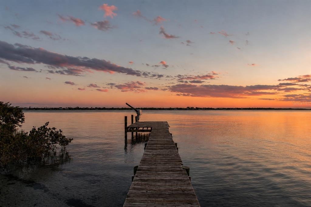 A wooden dock extends into calm water under a sunset sky with scattered clouds — 5216 13TH STREET, PALMETTO, FL