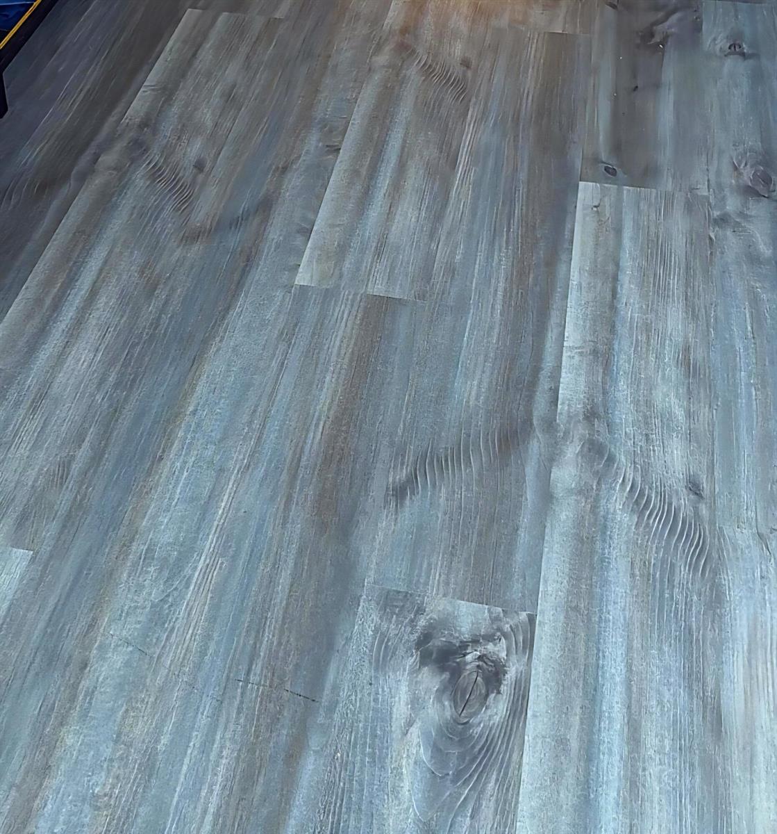 A close-up view of grey wood-look luxury vinyl plank flooring with visible grain patterns — 1830 Radius Drive # 526, Hollywood FL 33020, HOLLYWOOD, FL