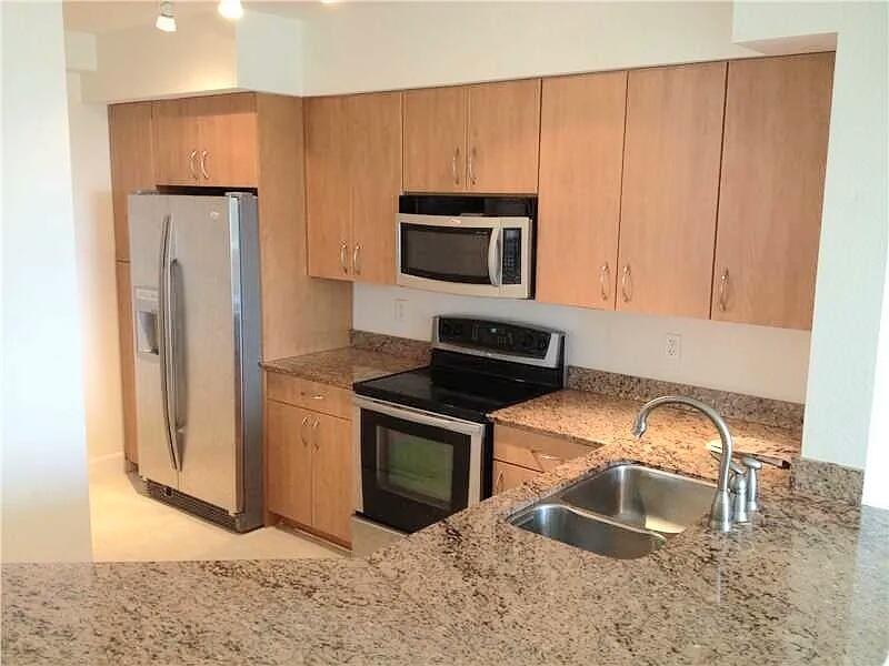 A kitchen features light wood cabinets, stainless steel appliances, and speckled granite countertops — 1830 Radius Drive # 526, Hollywood FL 33020, HOLLYWOOD, FL