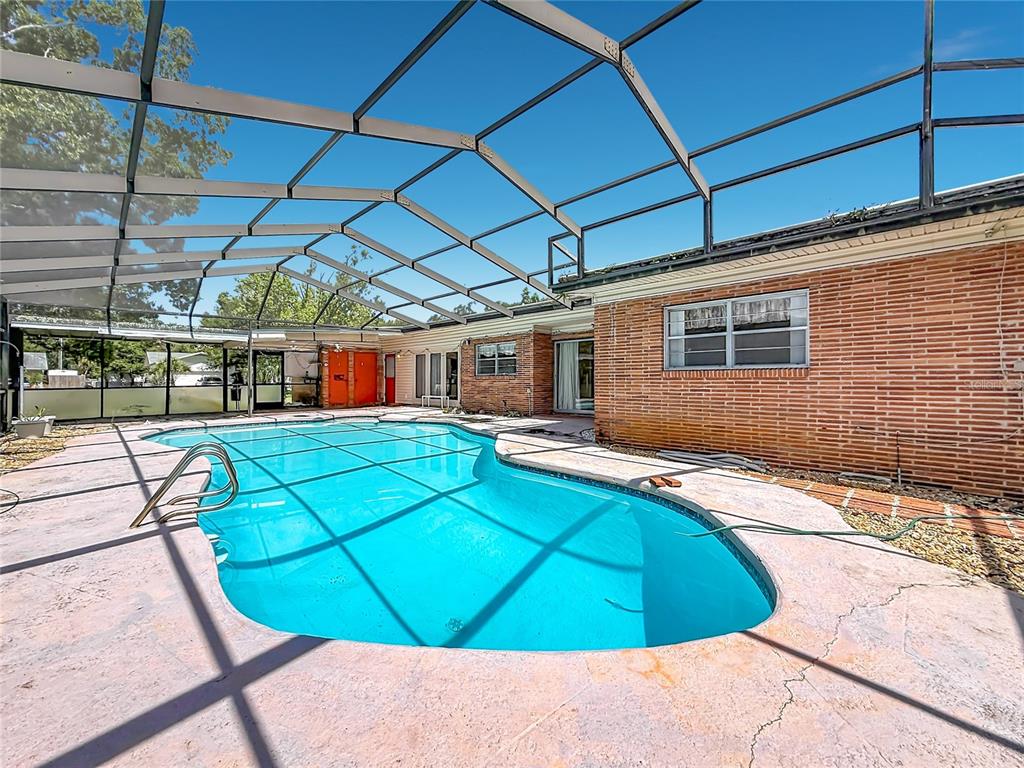A single-story brick house features a flat roof, a red front door, and a curved walkway — 605 COURTNEY DRIVE, TAMPA, FL