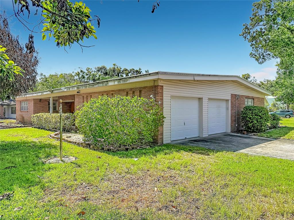 A swimming pool with a metal screen enclosure sits on a patio beside a brick house — 605 COURTNEY DRIVE, TAMPA, FL