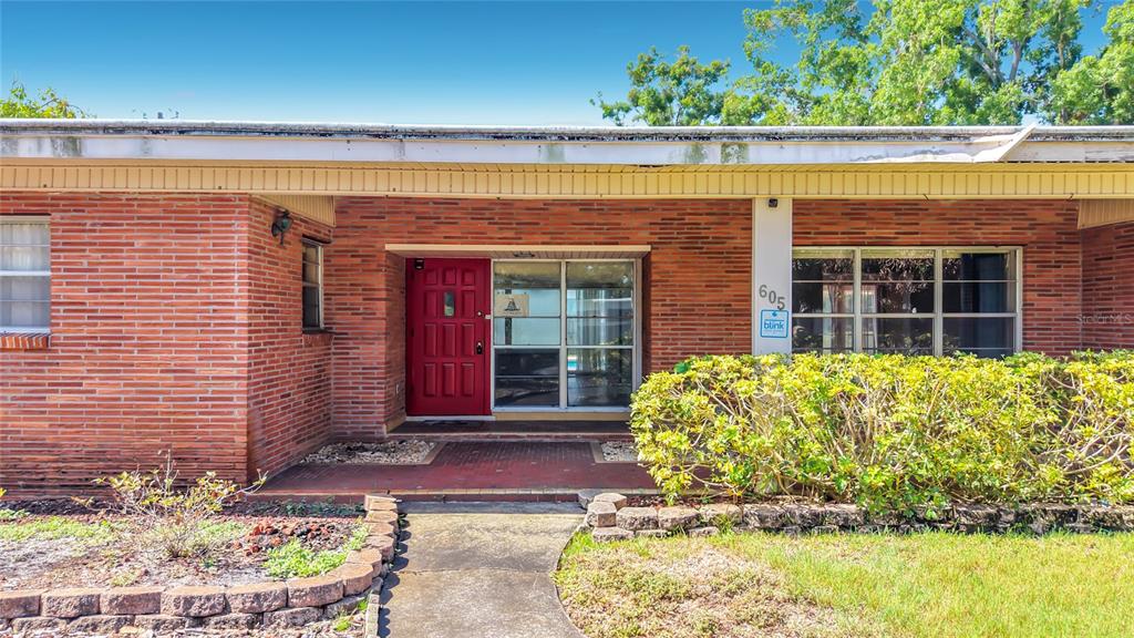 A single-story brick house with a red front door, a walkway, and mature landscaping — 605 COURTNEY DRIVE, TAMPA, FL