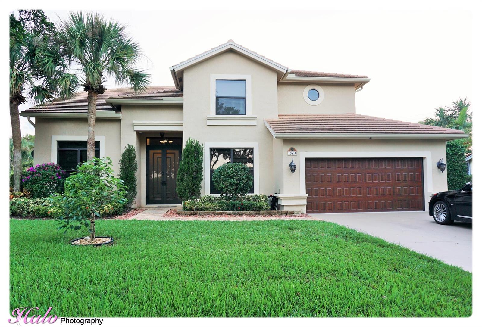 A two-story suburban house features a tan stucco exterior, a tile roof, and a garage — 10210 Lexington Estates Boulevard, Boca Raton FL 33428, BOCA RATON, FL