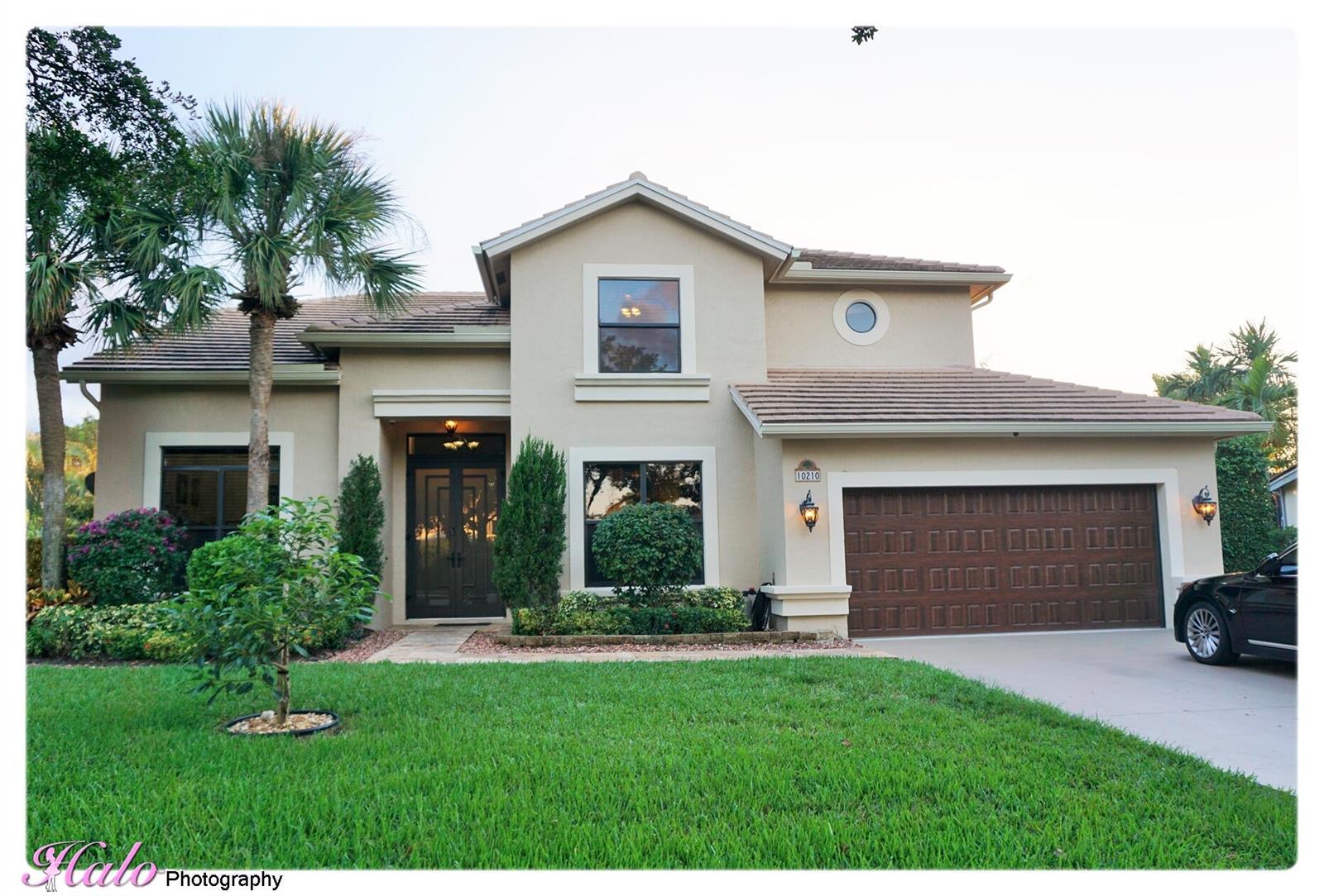 A two-story beige house with a brown tile roof, double garage, and front lawn — 10210 Lexington Estates Boulevard, Boca Raton FL 33428, BOCA RATON, FL