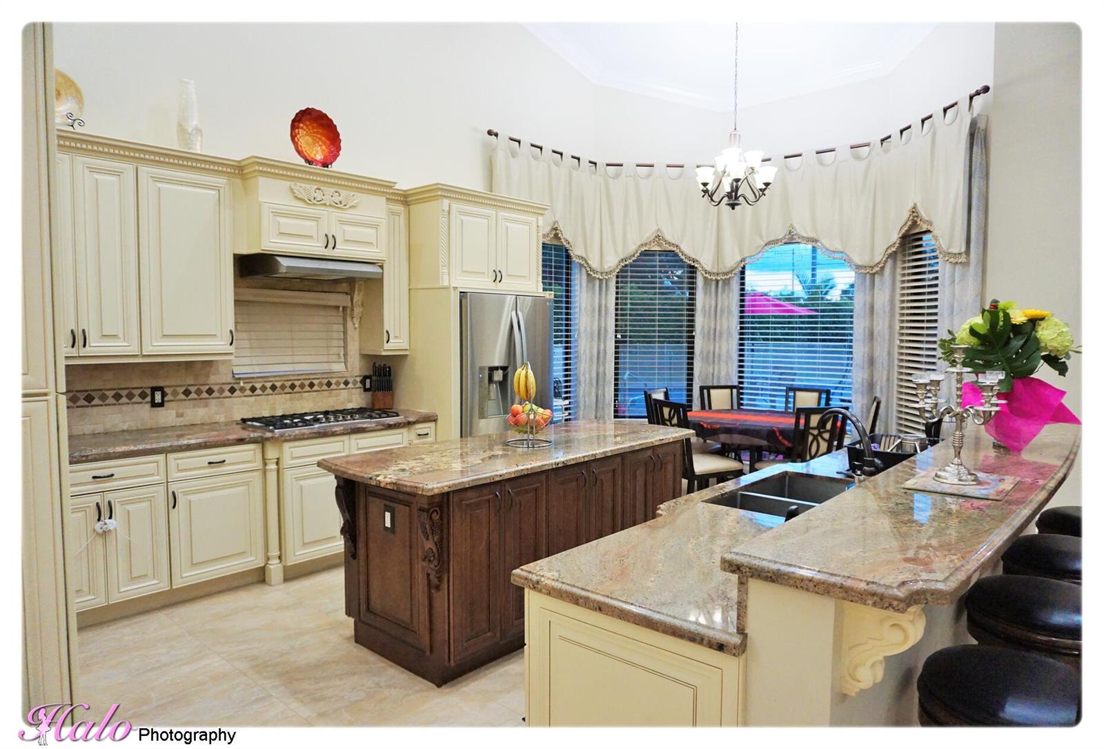 A kitchen with cream cabinets, a dark wood island, granite countertops, and a breakfast nook — 10210 Lexington Estates Boulevard, Boca Raton FL 33428, BOCA RATON, FL