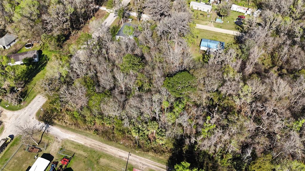 An aerial view shows a wooded lot surrounded by residential properties and dirt roads — 0 SW 15TH STREET RD, OCALA, FL