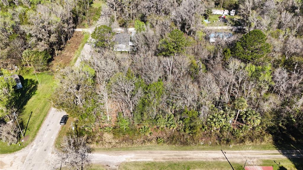 An aerial view shows a wooded lot with a small house and a dirt road — 0 SW 15TH STREET RD, OCALA, FL