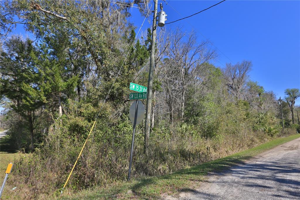 A street sign stands at the intersection of two dirt roads near a wooded area — 0 SW 15TH STREET RD, OCALA, FL