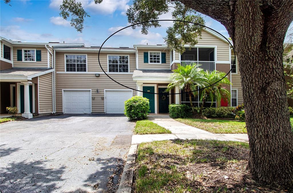 The exterior of a two-story townhouse features tan siding, a garage, and a screened balcony — 7405 VISTA WAY UNIT 203, BRADENTON, FL