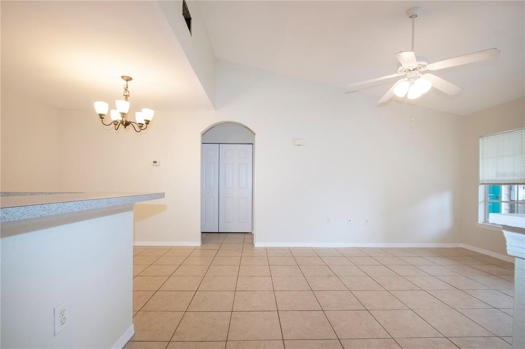 An open-concept room with tiled floors, a ceiling fan, a chandelier, and an arched doorway — 7405 VISTA WAY UNIT 203, BRADENTON, FL
