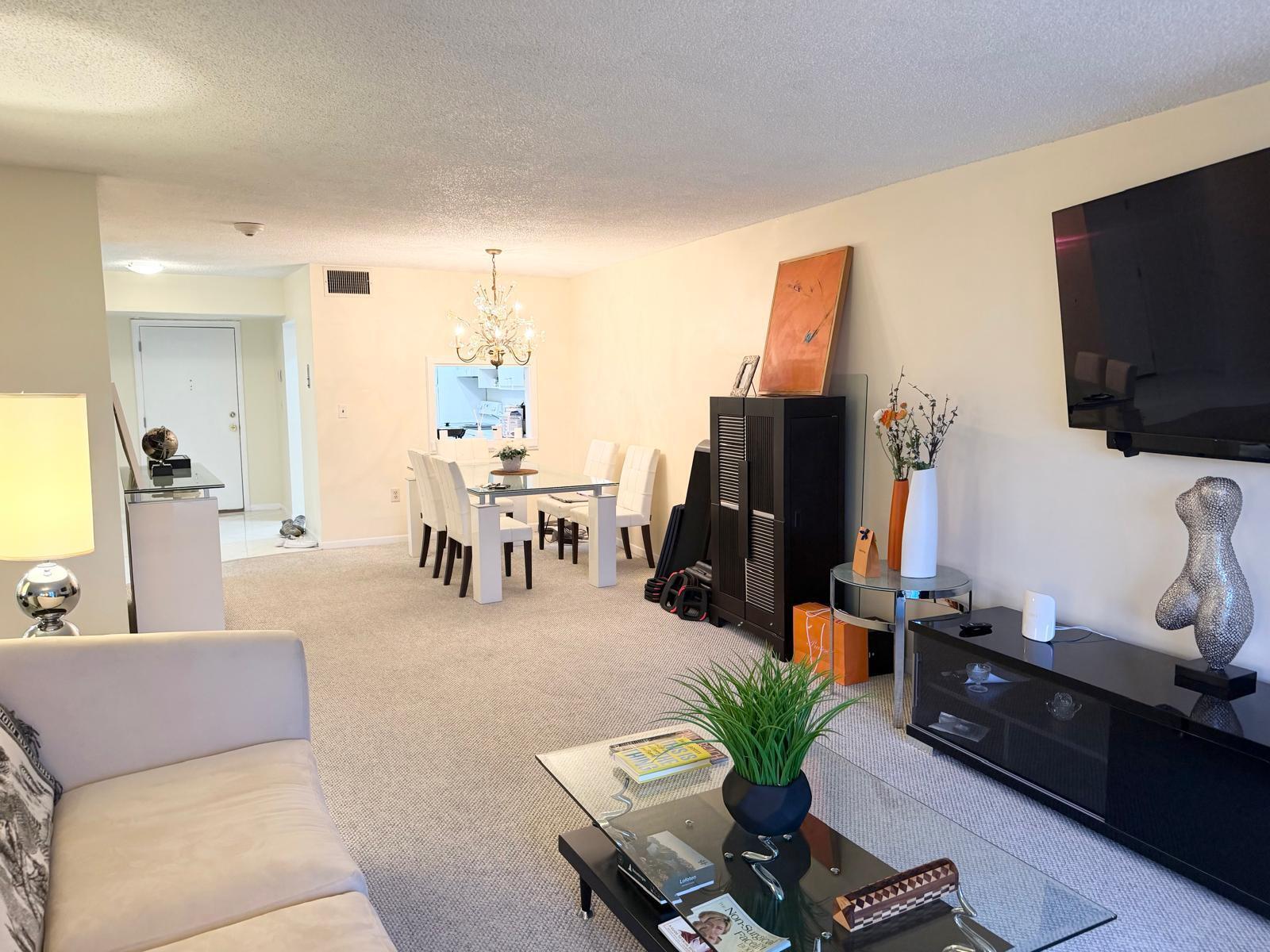 A living room and dining area with carpeted floors, a glass coffee table, and chandelier — 3605 S Ocean Boulevard # A433, South Palm Beach FL 33480, SOUTH PALM BEACH, FL