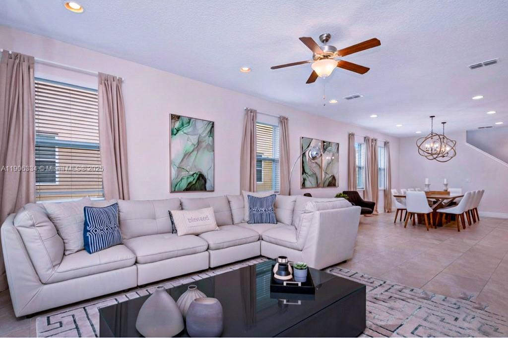 A living room with a large white sectional sofa, a coffee table, and a dining area — 7700 Fairfax, Kissimmee FL 34747, KISSIMMEE, FL