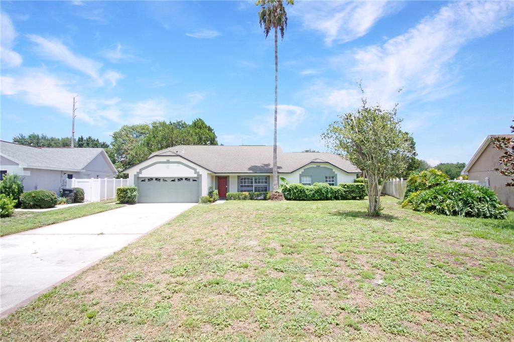 A single-story house with a two-car garage, a red front door, and a tall palm tree — 928 LOMA BONITA DRIVE, DAVENPORT, FL