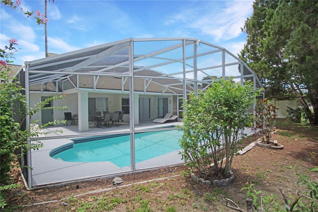 A swimming pool enclosed by a screen cage sits behind a house with a patio — 928 LOMA BONITA DRIVE, DAVENPORT, FL