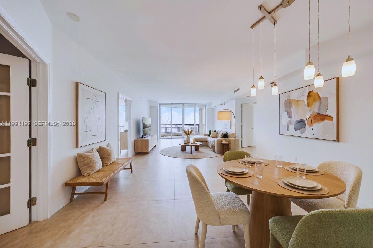 An open-concept living and dining area features light tile floors, modern furniture, and balcony access — 848 Brickell Key Dr # 2702, Miami FL 33131, MIAMI, FL