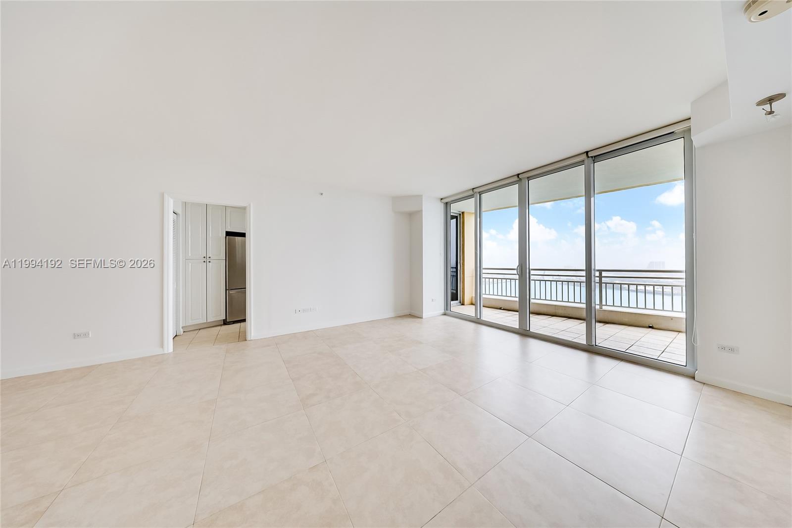 An empty living room features large floor-to-ceiling windows, tile flooring, and a balcony view — 848 Brickell Key Dr # 2702, Miami FL 33131, MIAMI, FL