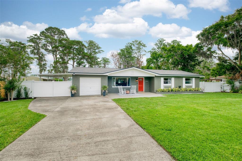 A grassy backyard features a fire pit surrounded by chairs overlooking a lake and dock — 5769 ROCKWOOD AVENUE, ORLANDO, FL