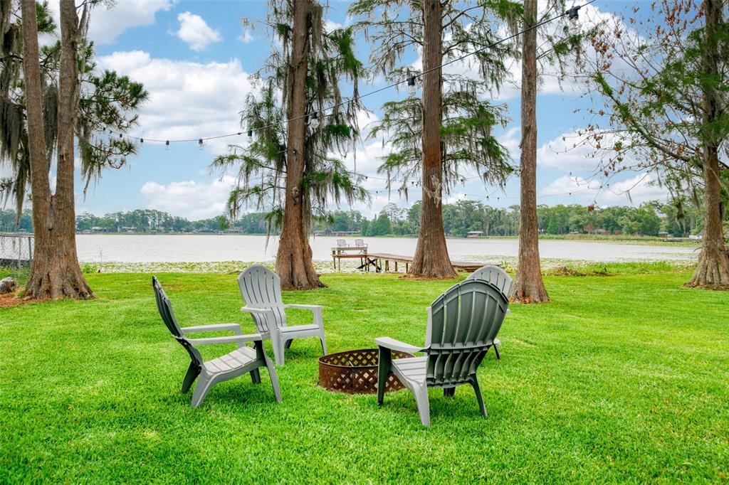 A wooden dock with two chairs extends into a lake covered in lily pads — 5769 ROCKWOOD AVENUE, ORLANDO, FL