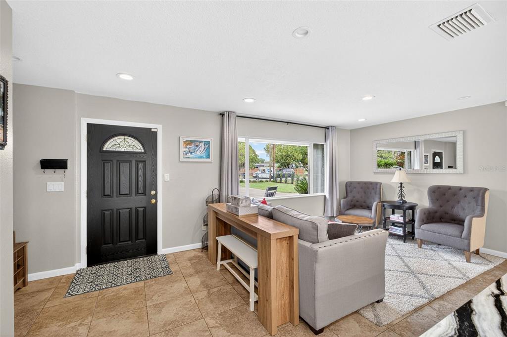 A living room with tile floors, a gray sectional sofa, and sliding doors overlooking a lake — 5769 ROCKWOOD AVENUE, ORLANDO, FL