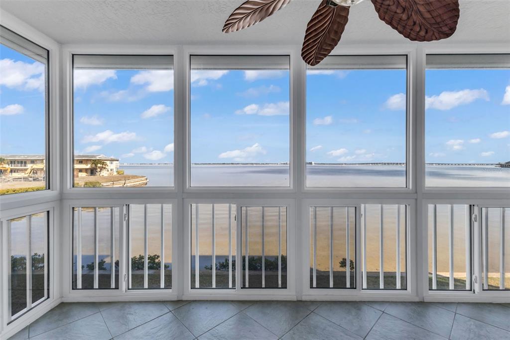 A sunroom with large windows overlooking a body of water and a tiled floor — 1650 W MARION AVENUE UNIT 123, PUNTA GORDA, FL