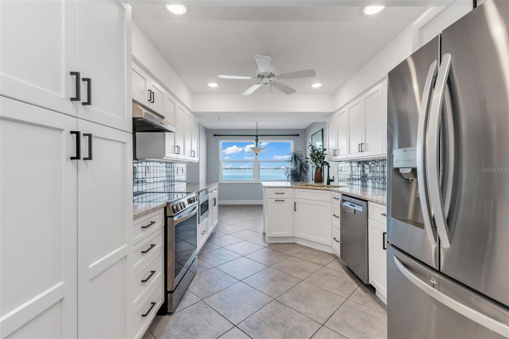 A white kitchen features stainless steel appliances, tile flooring, and a view of the water — 1650 W MARION AVENUE UNIT 123, PUNTA GORDA, FL