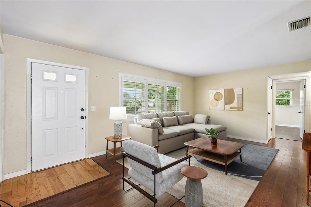 A living room features hardwood floors, a sectional sofa, an armchair, and a front door — 1500 39TH STREET N, ST PETERSBURG, FL