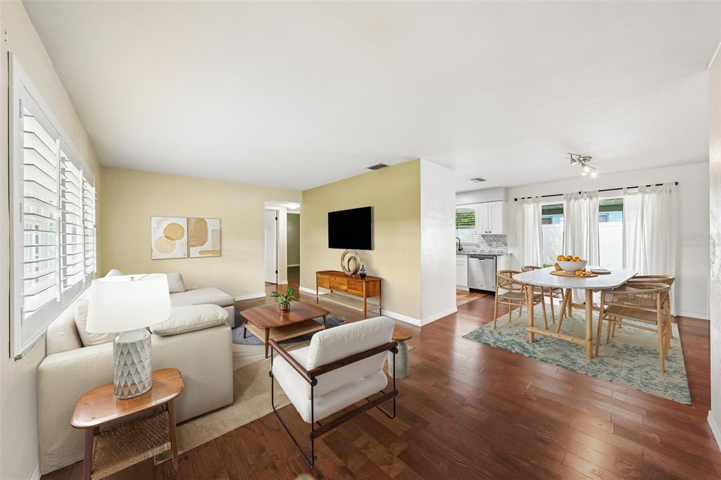 A living room and dining area with hardwood floors, white walls, and neutral furniture — 1500 39TH STREET N, ST PETERSBURG, FL