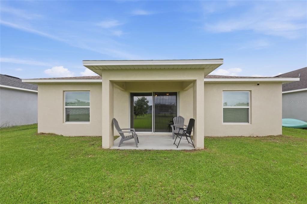 The exterior view shows the back of a house with a covered concrete patio — 3640 GRUBBS STREET, MOUNT DORA, FL