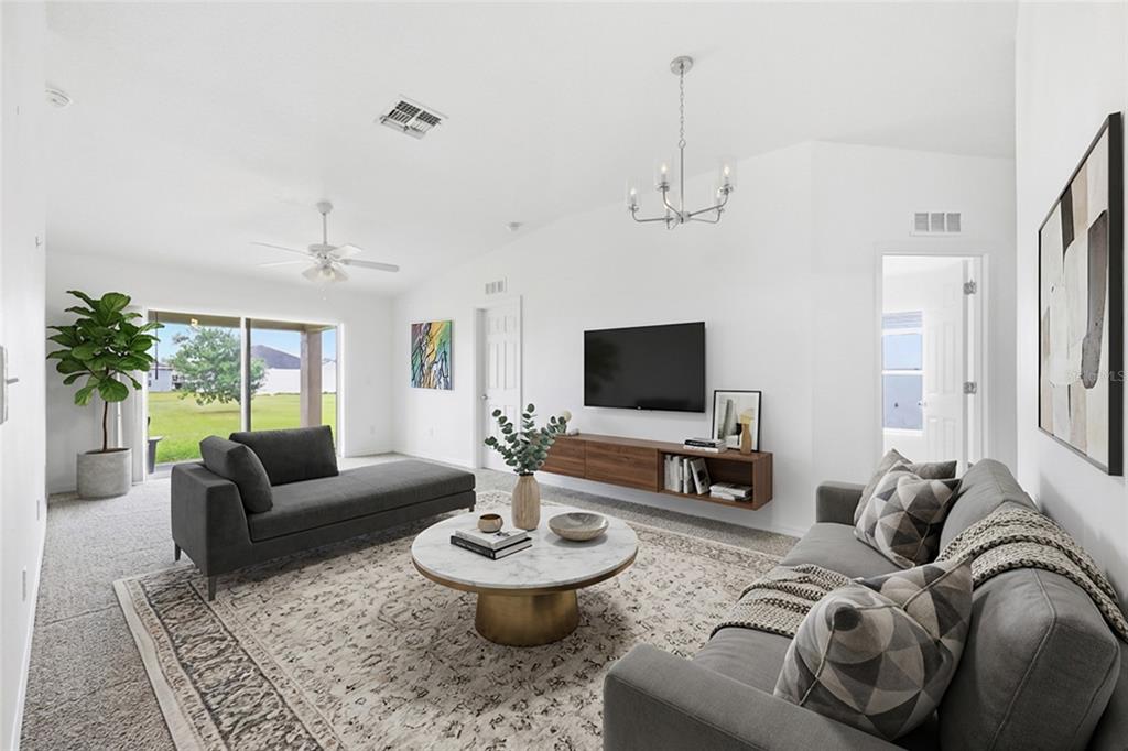 A living room features a gray sofa, a marble coffee table, and a wall-mounted television — 3640 GRUBBS STREET, MOUNT DORA, FL