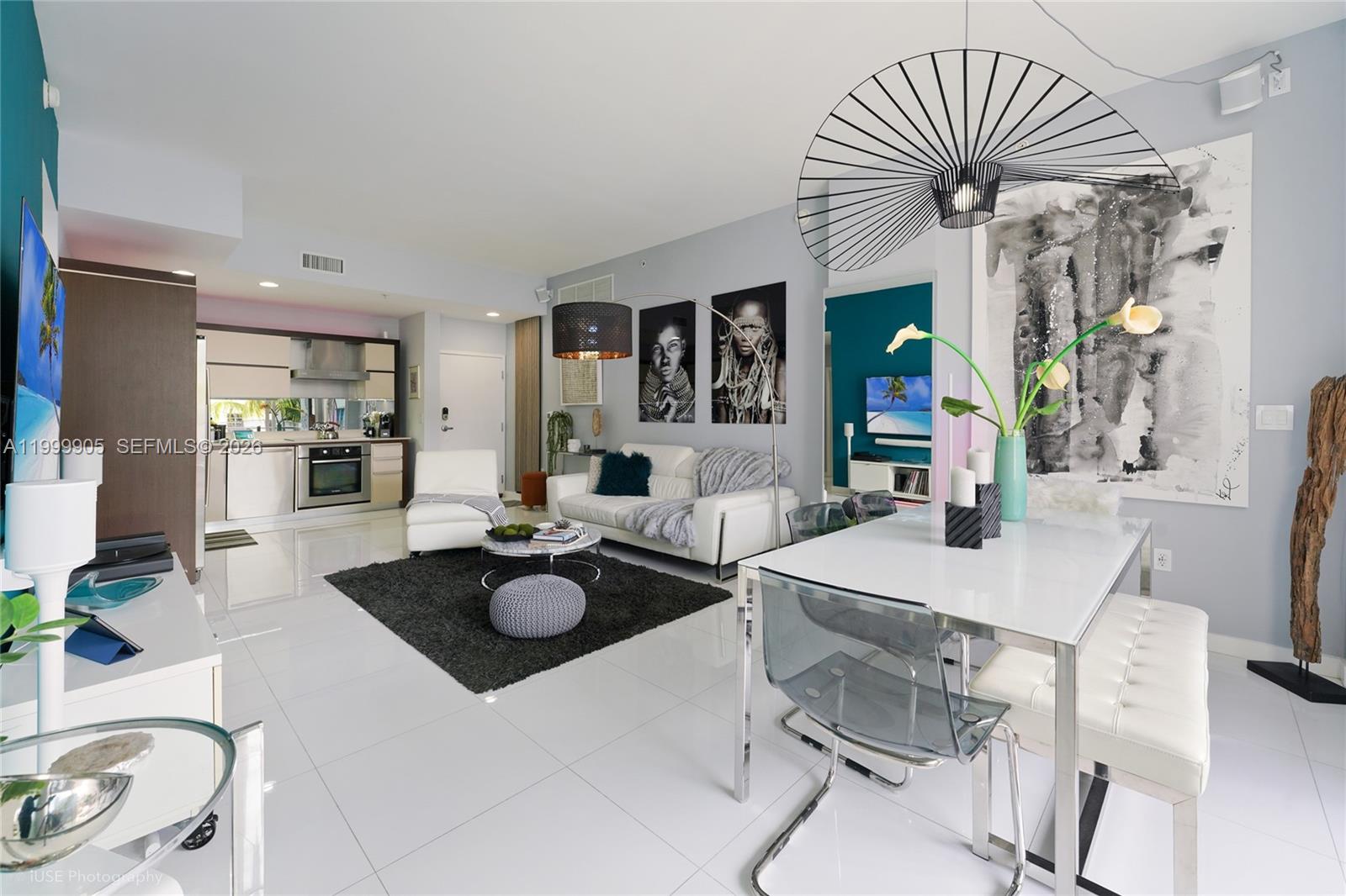 A modern open-concept living and dining area features white tile floors and contemporary decor — 2100 Park Ave # 210, Miami Beach FL 33139, MIAMI BEACH, FL