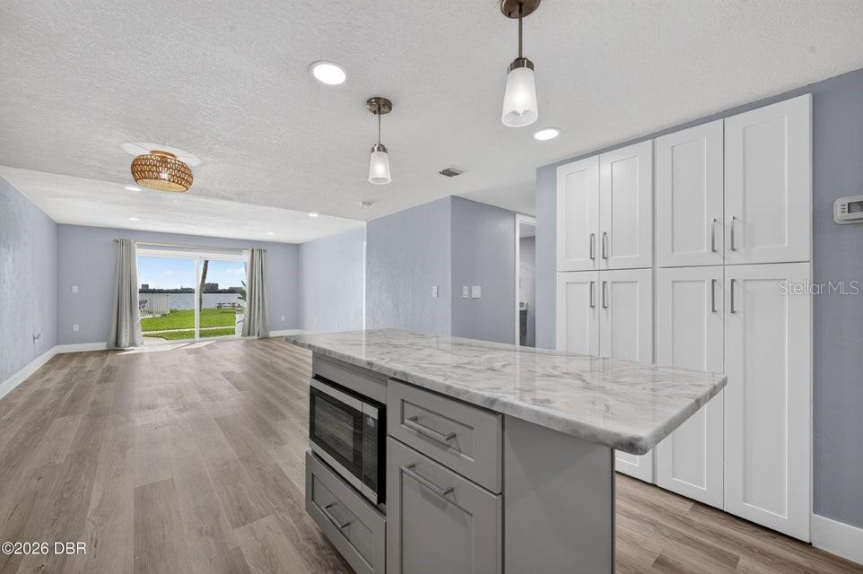 A kitchen island with a marble countertop sits in front of tall white cabinets — 3131 S RIDGEWOOD AVENUE UNIT 108, SOUTH DAYTONA, FL