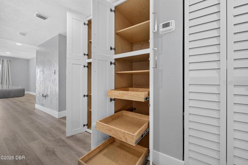 A white pantry cabinet with pull-out wooden drawers stands in a room with light flooring — 3131 S RIDGEWOOD AVENUE UNIT 108, SOUTH DAYTONA, FL