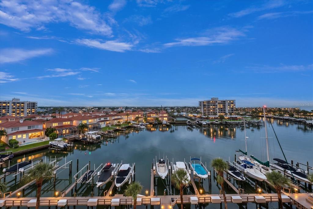 An elevated view of a marina with docked boats and residential buildings under a blue sky — 1621 GULF BOULEVARD UNIT 607, CLEARWATER BEACH, FL
