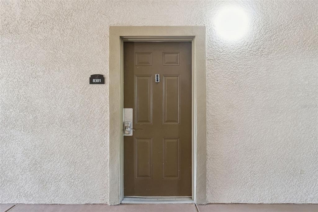 A brown exterior door with a keypad lock and a unit number sign on stucco — 1351 TUSCAN TERRACE UNIT 8301, DAVENPORT, FL