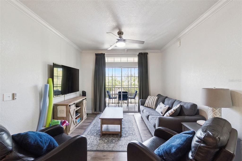 A living room features a gray sofa, two leather armchairs, a television, and a balcony — 1351 TUSCAN TERRACE UNIT 8301, DAVENPORT, FL