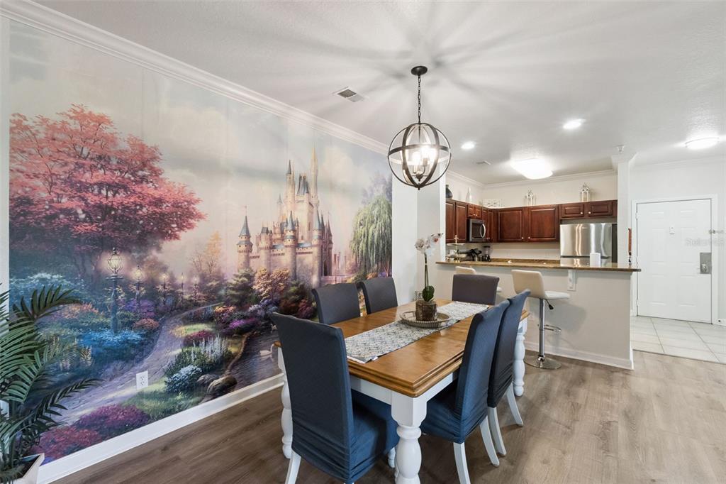 A dining area features a large castle mural, a wooden table, and an open kitchen — 1351 TUSCAN TERRACE UNIT 8301, DAVENPORT, FL