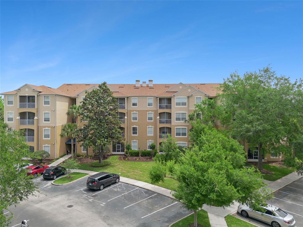 An exterior view of a multi-story apartment building with a parking lot in front — 2821 ALMATON LOOP UNIT 203, KISSIMMEE, FL