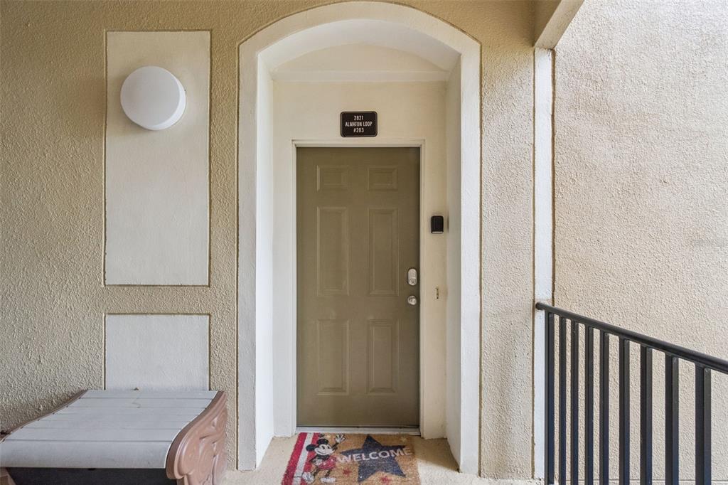 An exterior view of a tan apartment door with a Mickey Mouse welcome mat — 2821 ALMATON LOOP UNIT 203, KISSIMMEE, FL