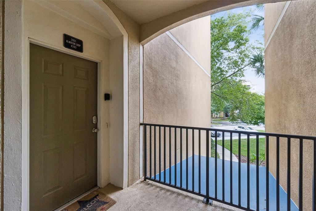An exterior view of an apartment entrance with a brown door and a metal railing — 2821 ALMATON LOOP UNIT 203, KISSIMMEE, FL