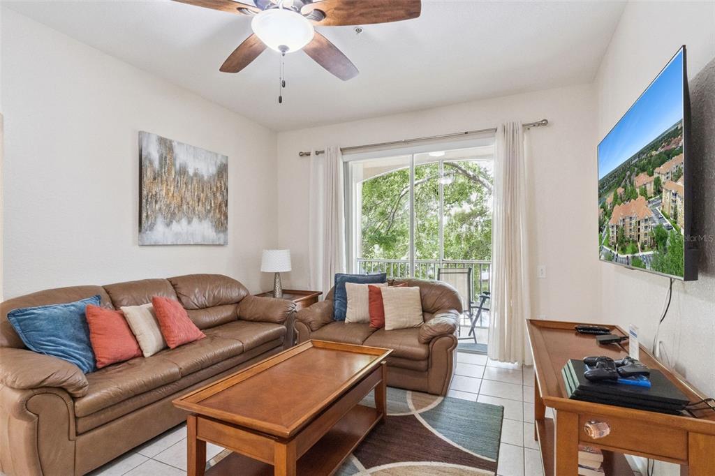 A living room features brown leather sofas, a wooden coffee table, and a balcony view — 2821 ALMATON LOOP UNIT 203, KISSIMMEE, FL